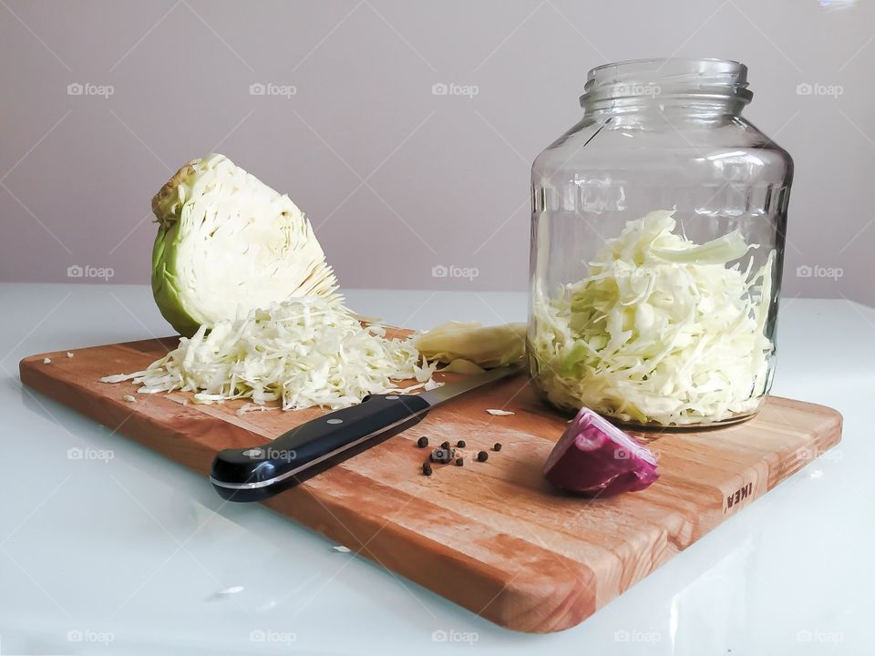 Cabbage sliced for pickling on a cutting board and in a jar