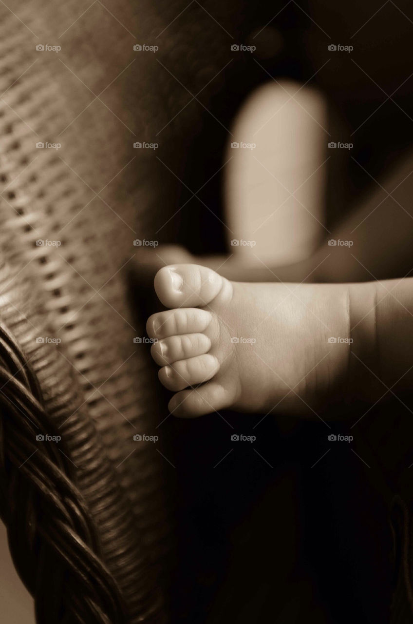 Baby feet in sepia tones on wicker basket