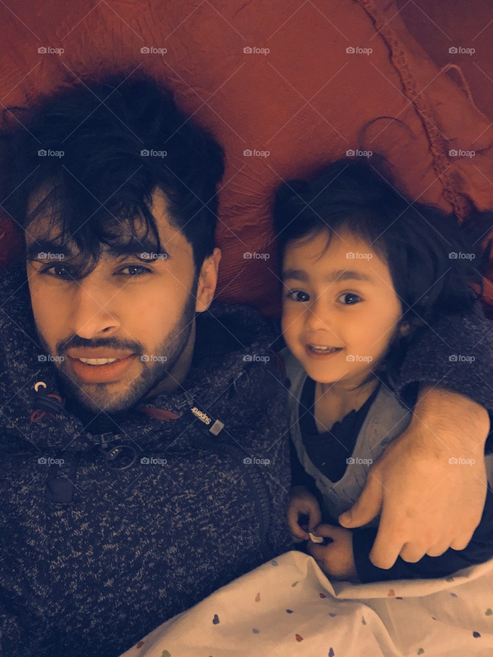 High angle view of father and daughter lying on bed