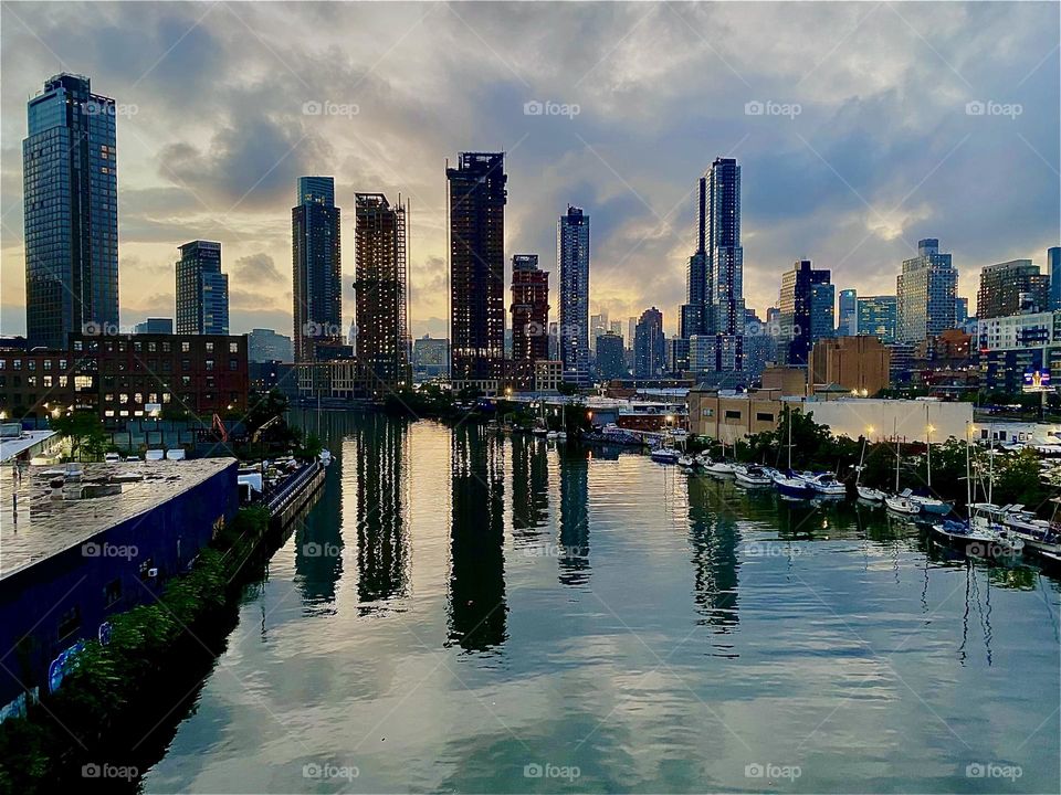 This is the familiar sight of the „East River“ at „Newtown Creek“ in LIC from the „Pulaski Bridge“. „Greenpoint“, Bklyn is on the left, „Queens“ to the right and in the far distance straight ahead „Manhattan“. 2023. Hypnotic Productions
