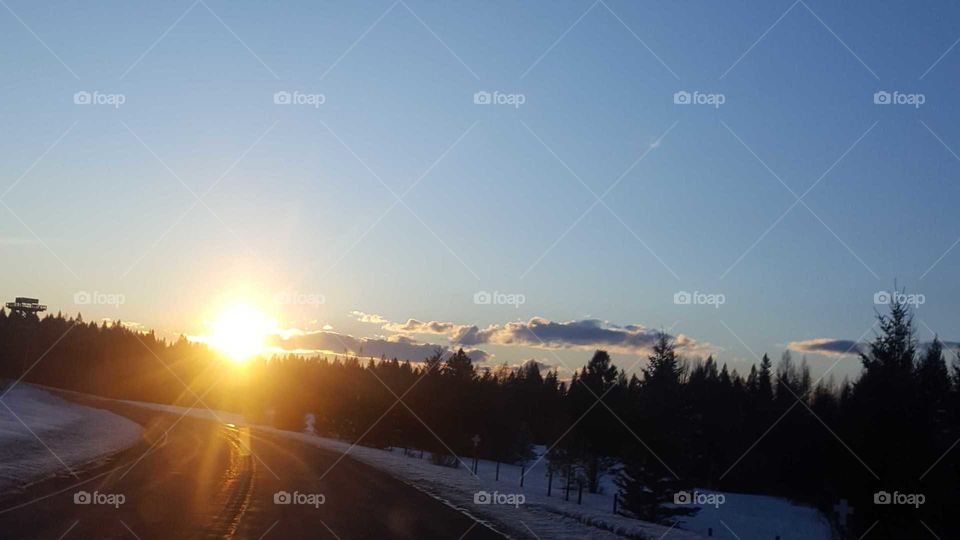 Sun setting on turn in road with snow