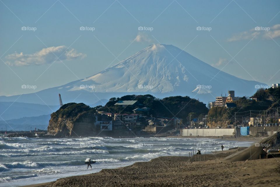 Strong wind driving waves onto the black volcanic sands of Kamakura beach with majestic Mount Fuji in the background 