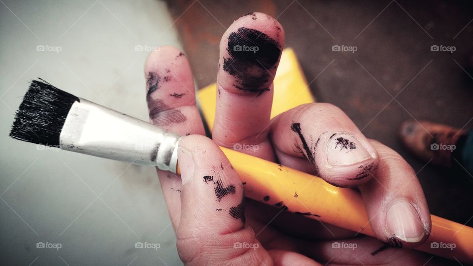 Dedos sujos de tinta. Mão com pincel.
