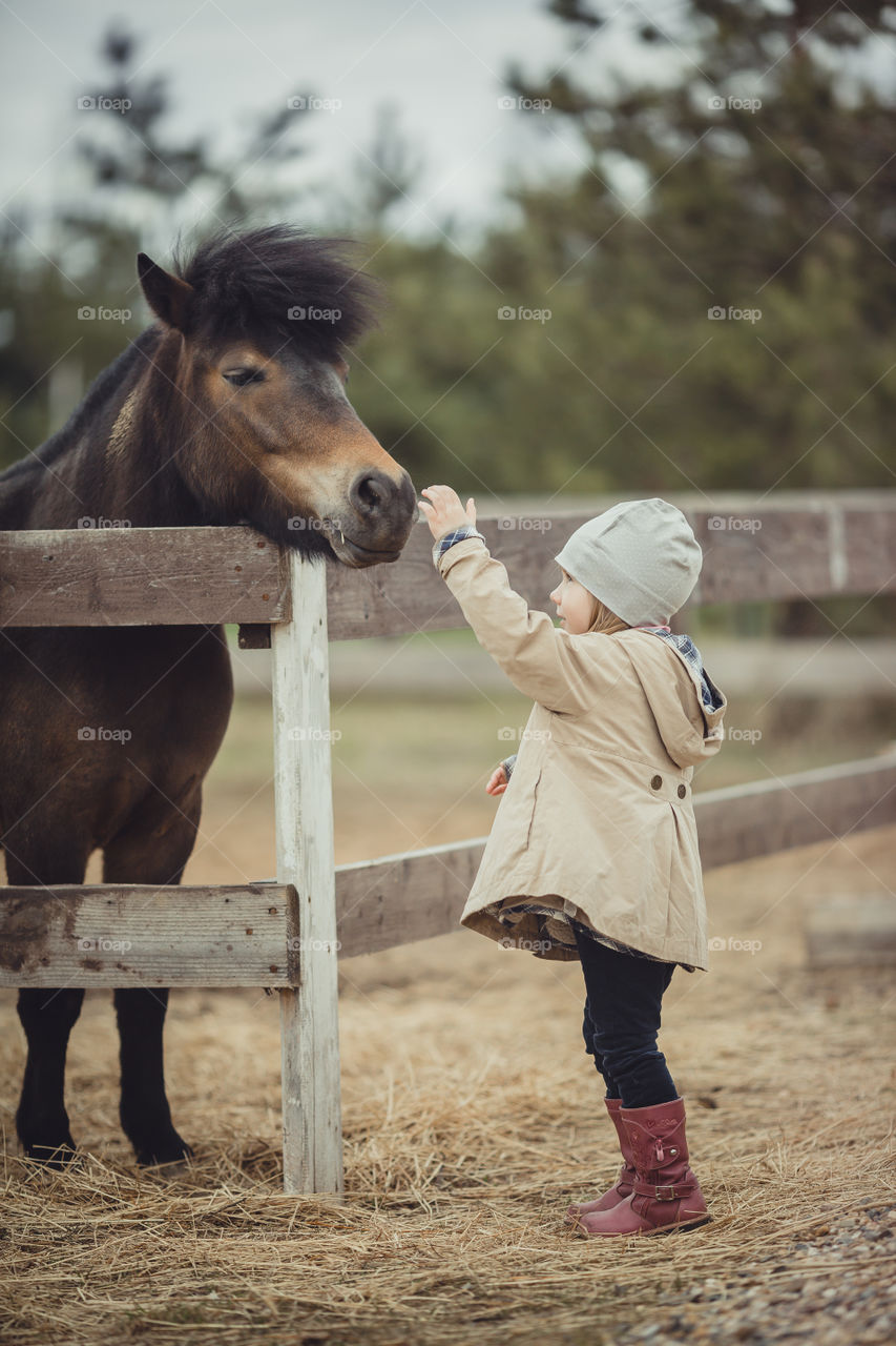 Little girl with pony, outdoor portrait 