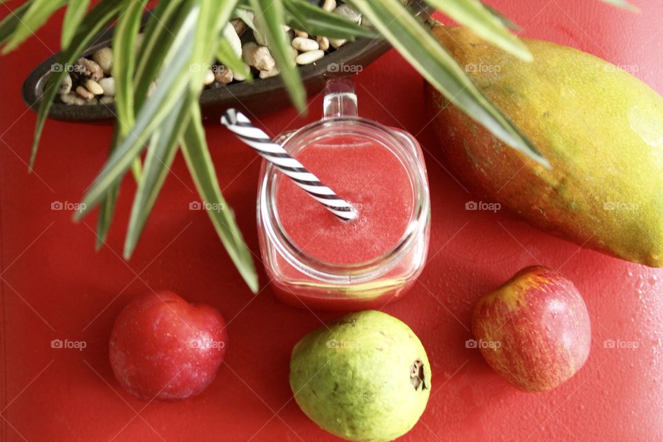 Fruits and tropical juice on red background