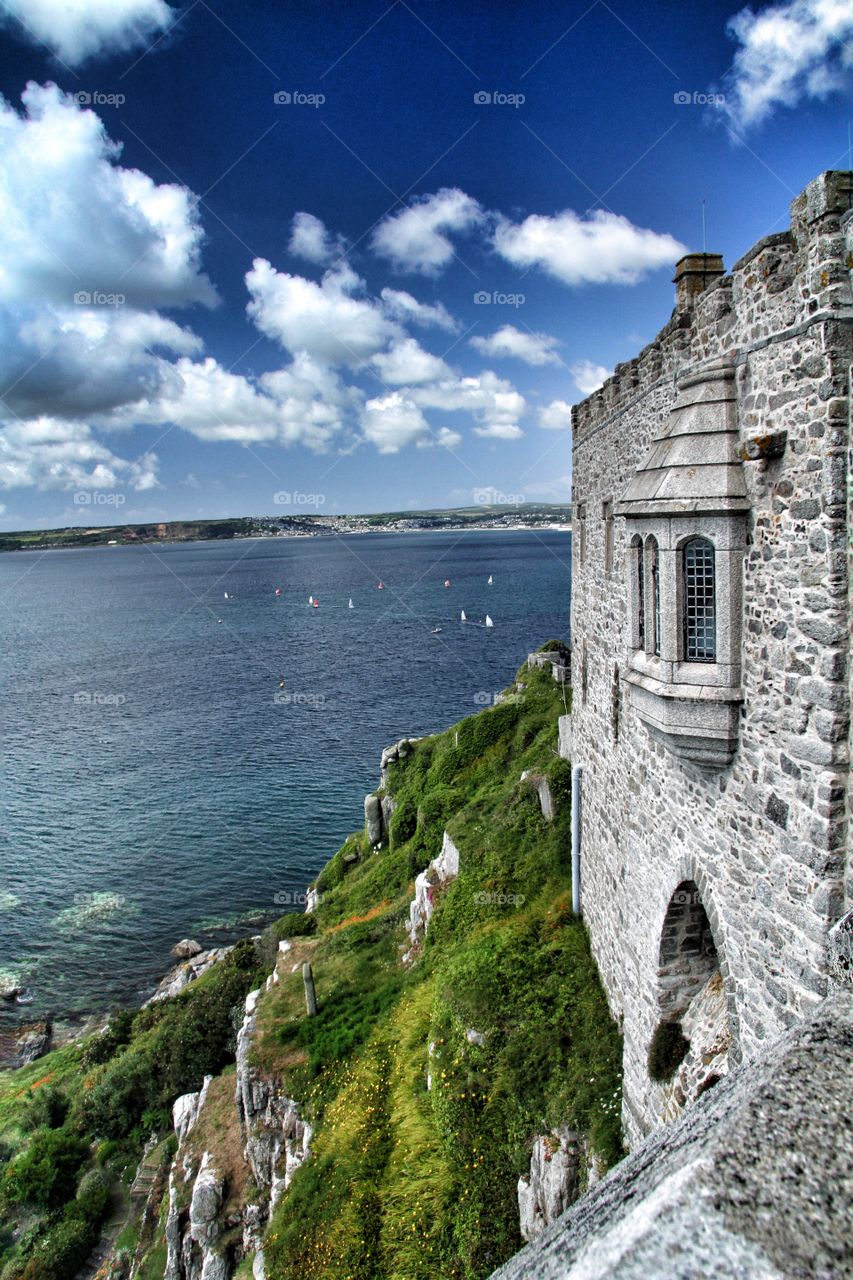 Castle With A Sea View. A stone castle looks out over the ocean on a bright, blue, sunny day.