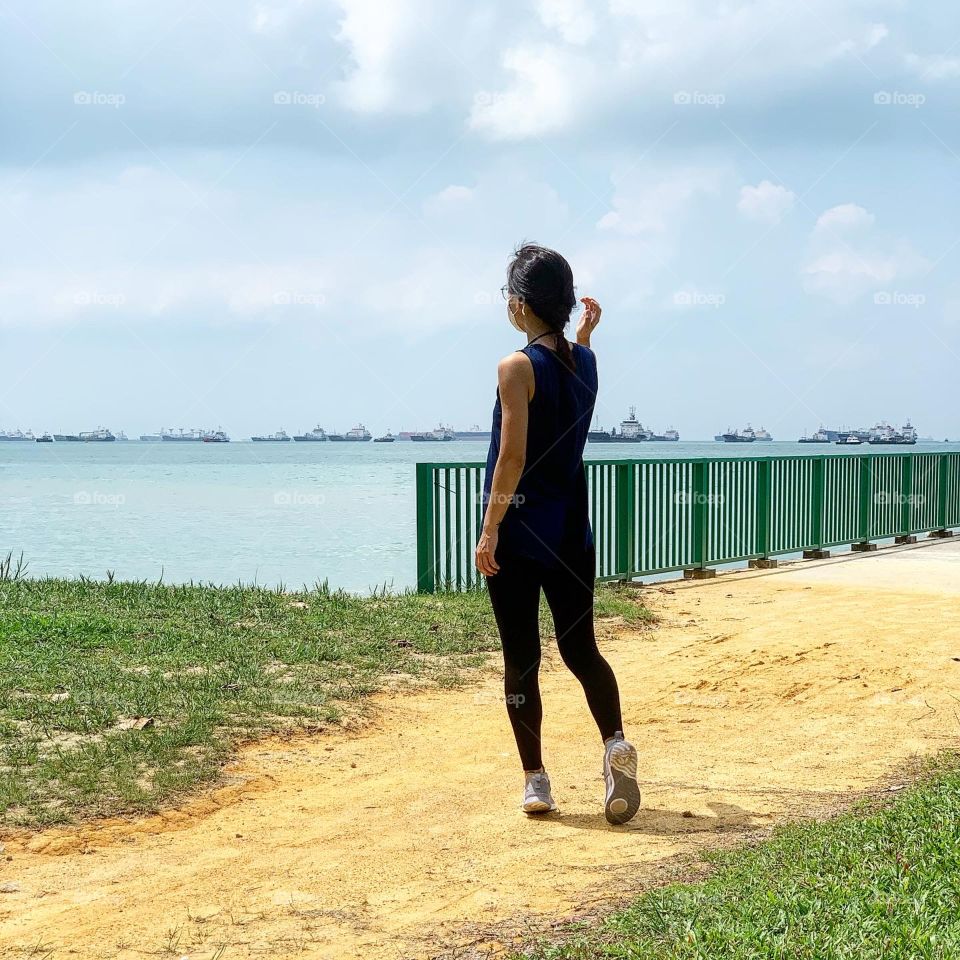 Altheletic lady back View in black leggings facing the sea in Asia 