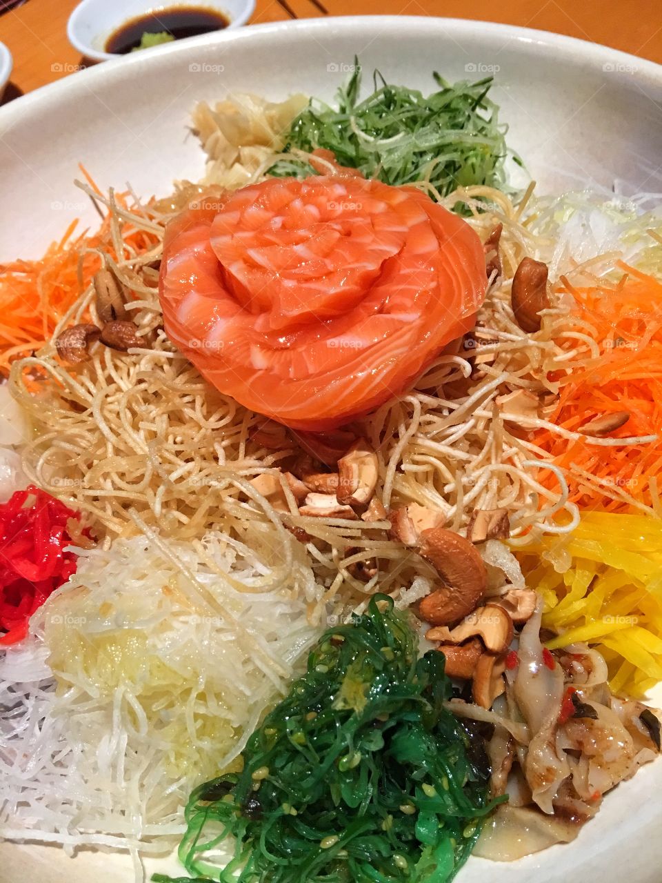 "Yee Sang" a popular Chinese New Year dish originating from Malaysia. Typically a combination of preserved and pickled shredded fruit and vegetables, crunchy fried crackers, oil, sweet sauce and the main ingredient which is usually raw fish like Japanese "sashimi", in this case salmon. Before consuming it, a ritual, "Loh Sang" where everyone present participates in mixing and tossing the ingredients with chopsticks