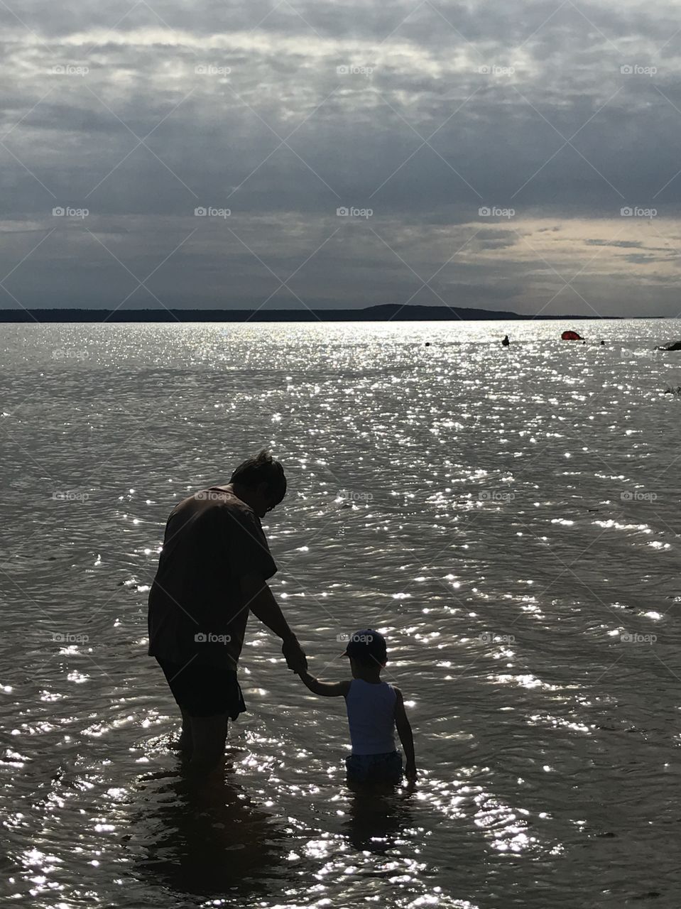 Man and child in the water by a beach