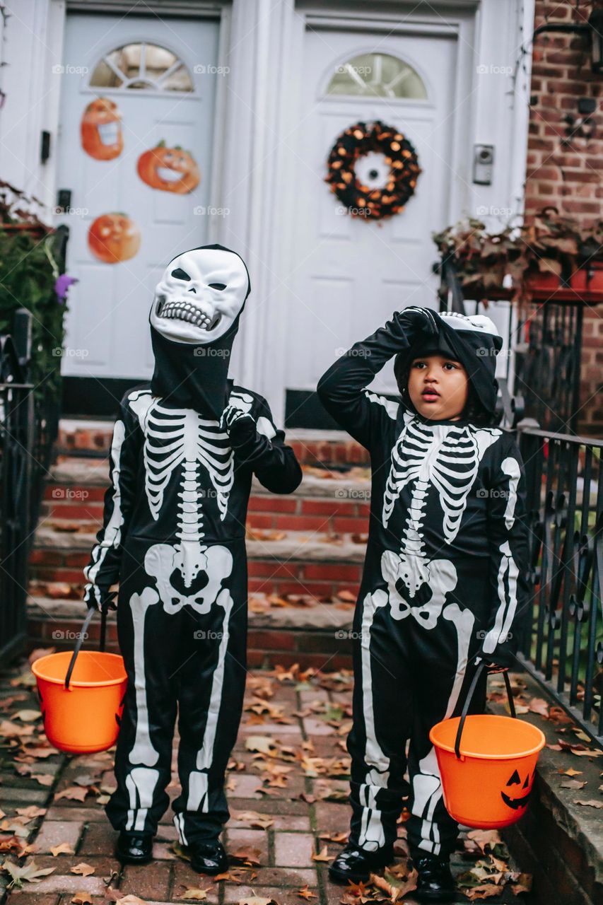 Children in skeleton costumes trick or treating in Halloween , orange and black 
