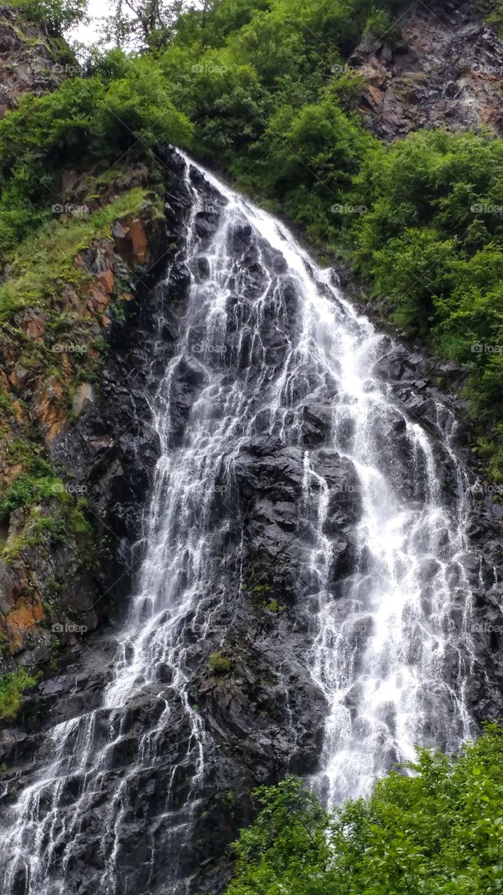 Cascading waters fan out over black granite rocks in Alaska's pristine wilderness.