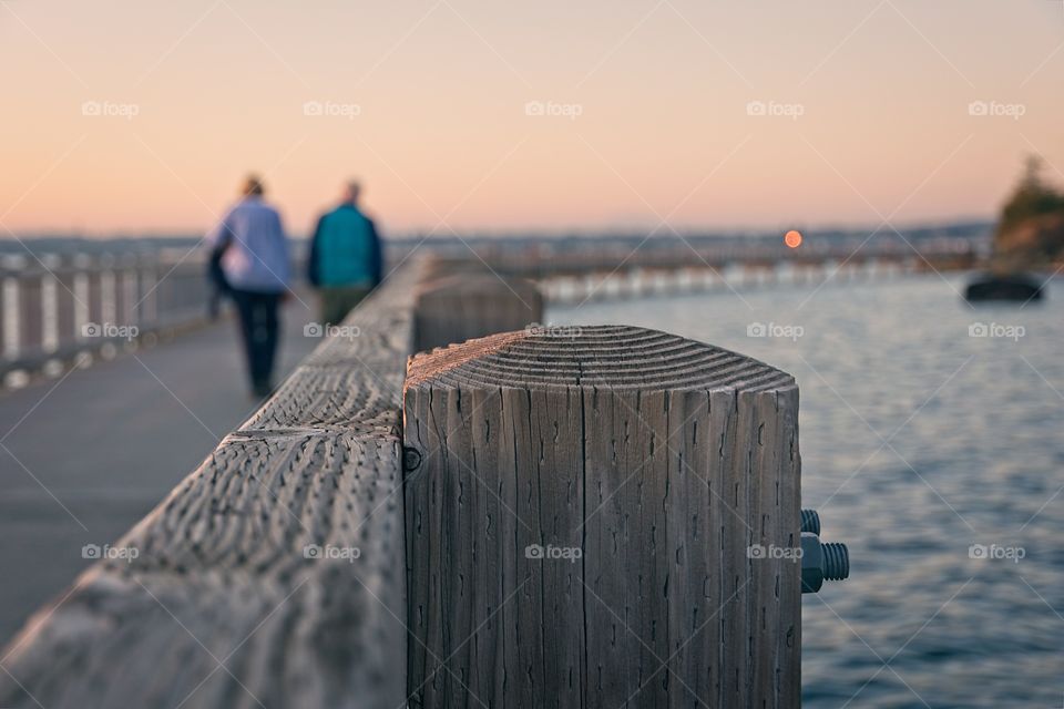 Couple walking by the shore in a bridge during sunset