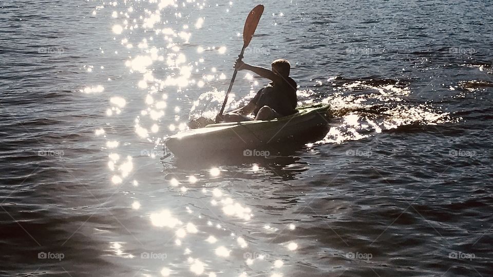 Gorgeous reflection of light on lake while boy is canoeing makes for a beautiful photo showing water’s beauty! 
