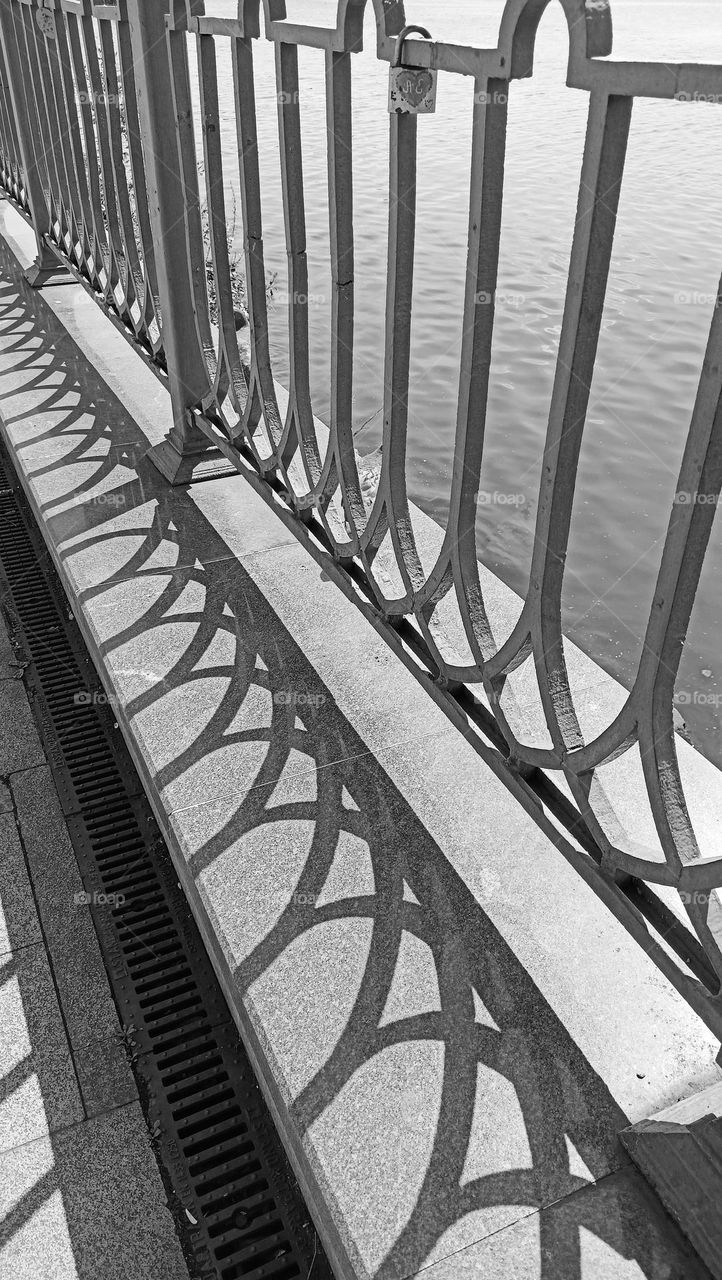 black and white photography, fence, railing, pond shore, stone, granite, grey, parallel lines, melancholy