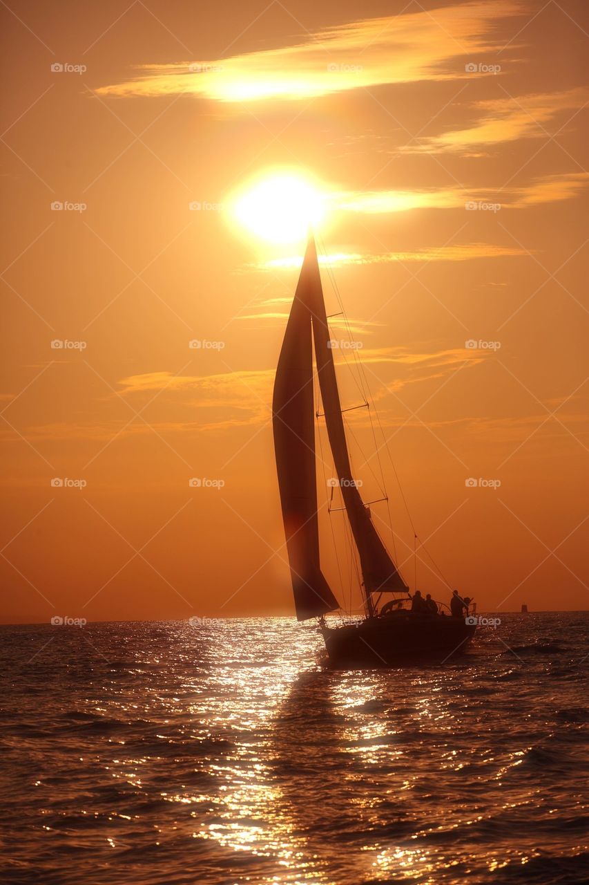 Yacht sailing against a setting sun