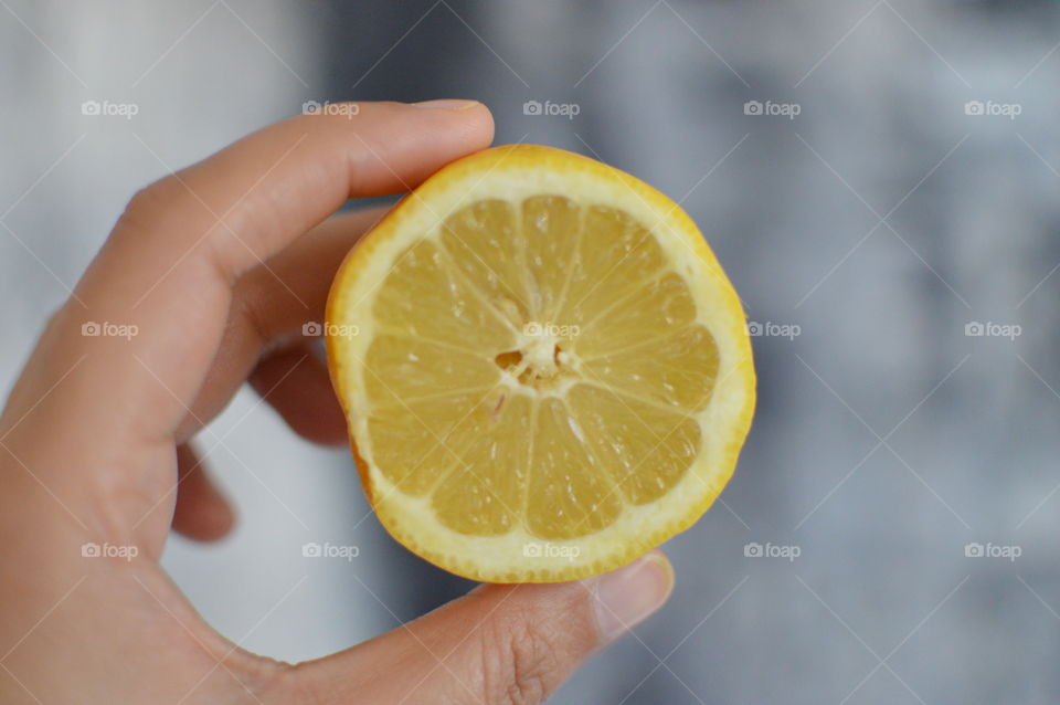 Close-up of hand holding yellow lemon