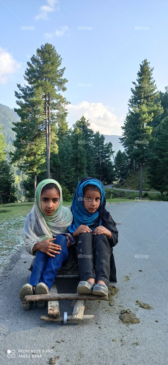 An inocent pair of siblings playing on slopey road in Thick Woods at remote beatiful village called Aharbhal near waterfall Aharbhal in Kashmir valley J&K.