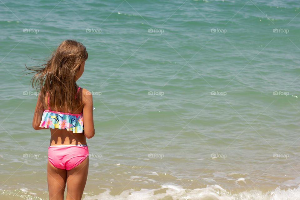 Back of caucasian girl looking at blue sea