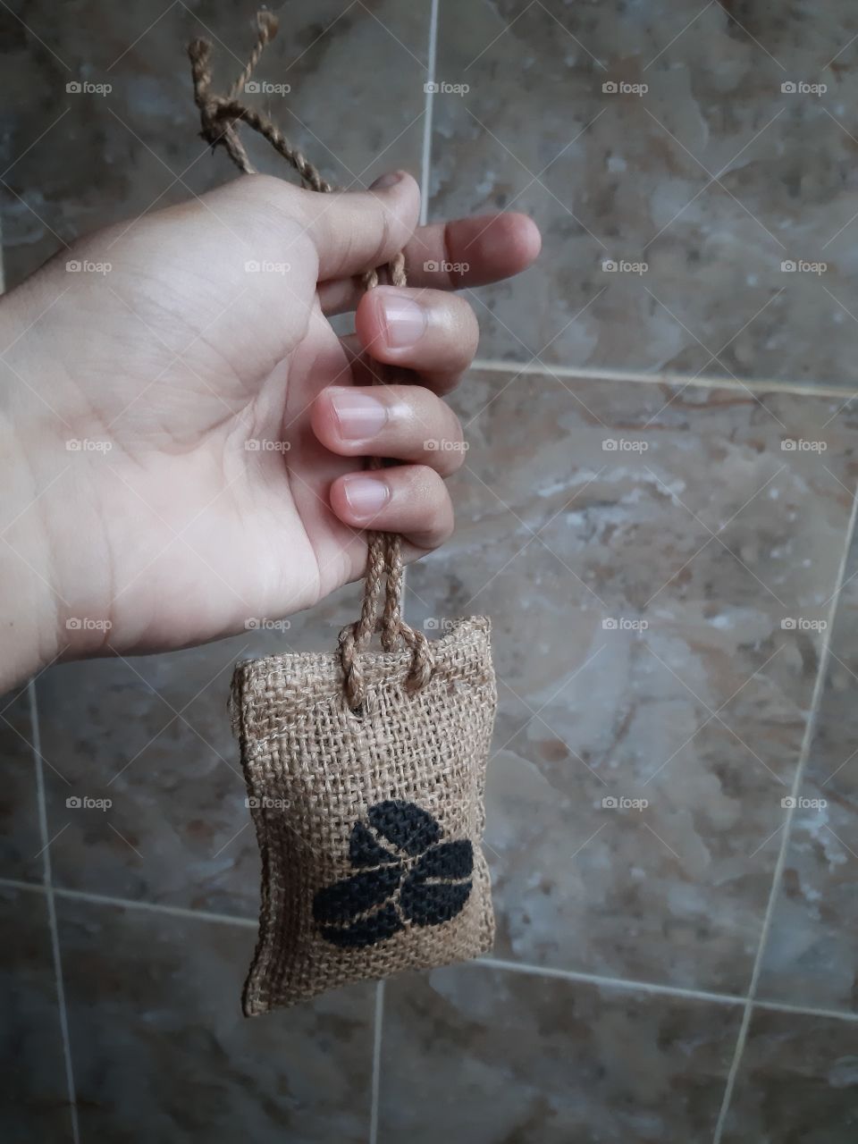 An air freshener is held by the left hand