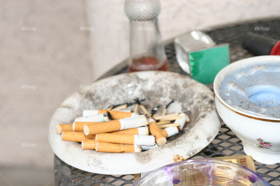 Close up of a dirty ashtray full of cigarettes and matches.