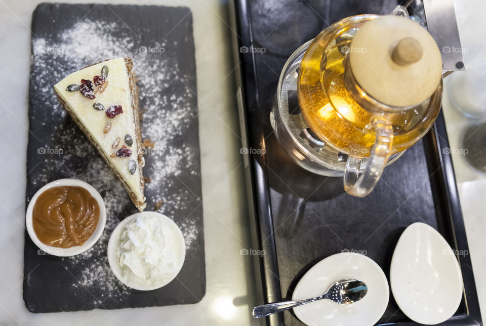 Top view of delicious carrot cake and teapot with hot tea