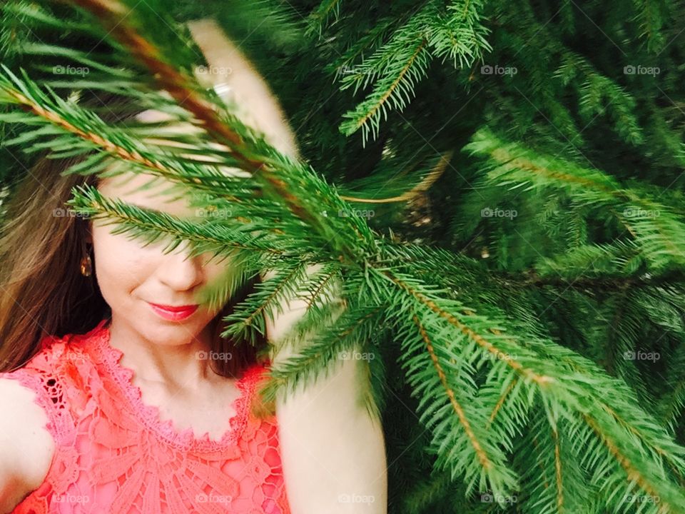 Portrait of woman with red lips surrounded by pine cone trees