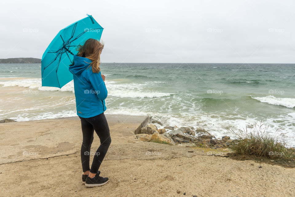 girl standing at the coast with her umbrella