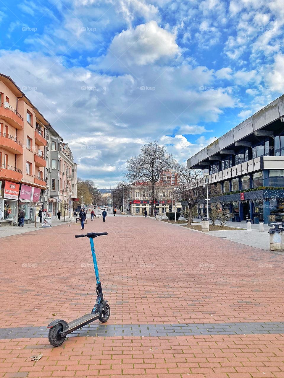 A public rental scooter is in the middle of the street 