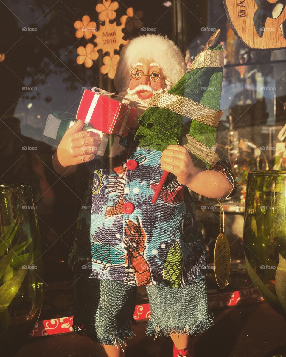 A Hawaiian Santa Claus in full tourist Hawaiian attire in a store window. 