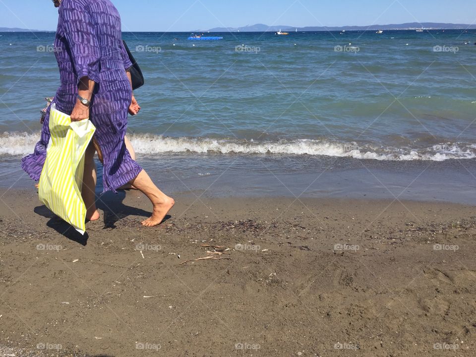 Woman with yellow bag walks on the beach