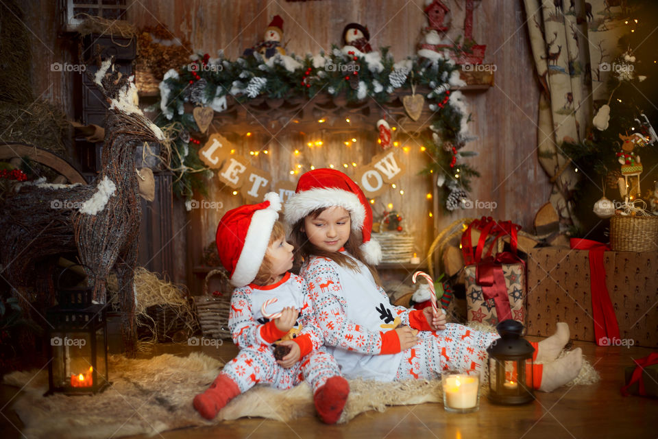 Little sisters near fireplace at Christmas Eve 