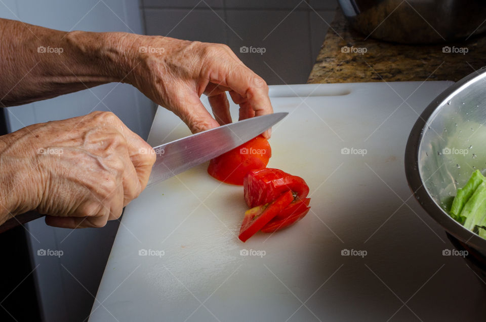 slicing the tomato to put it in the salad.