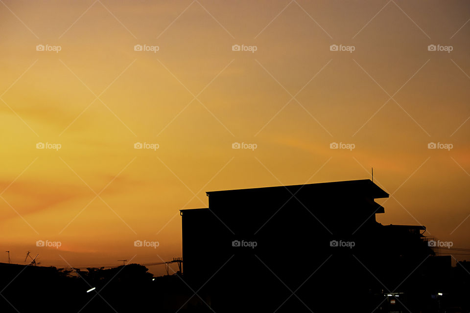 Beautiful light of Sunset with clouds in the sky reflection behind the building.