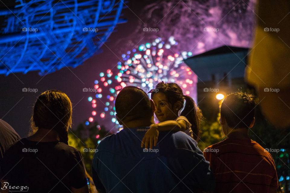 Father and Daughter... A father is holding his daughter during a firework show to celebrate America's independence.