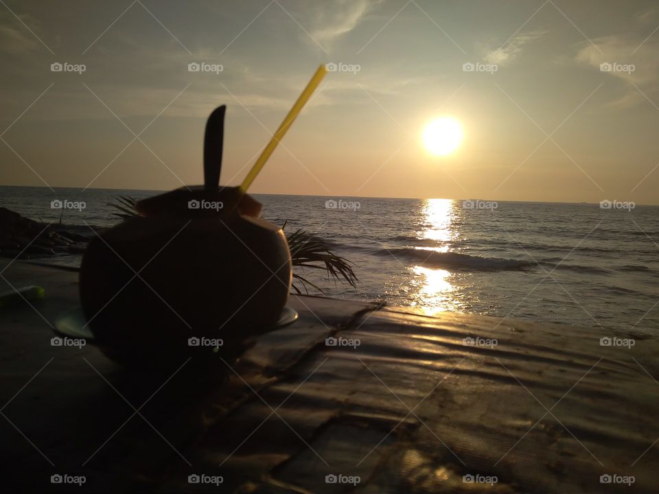Menikmati keindahan sunset ditemani sebuah kelapa muda