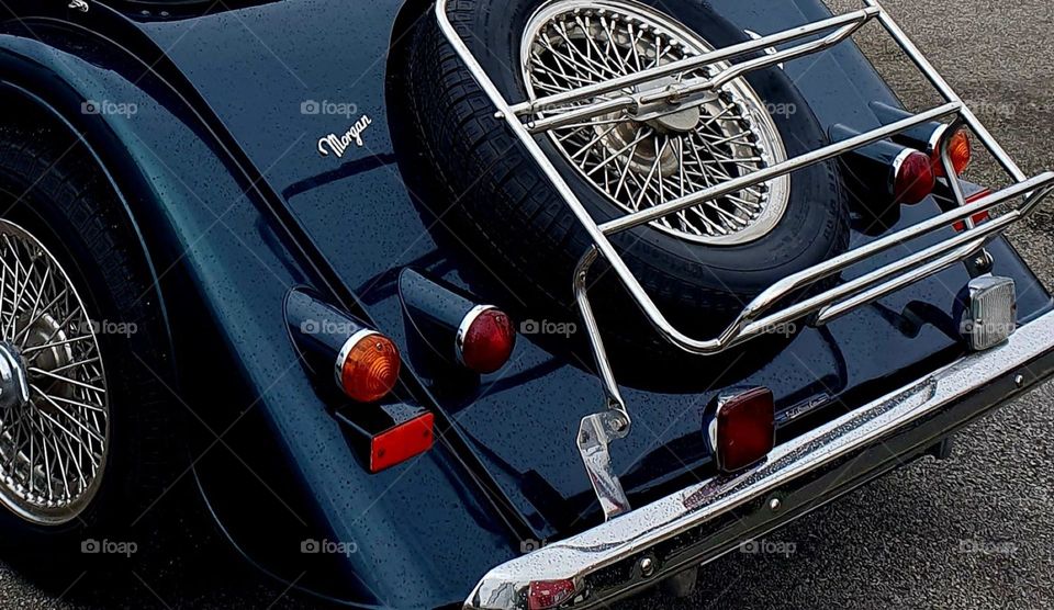 Shot of the rear of a dark green Morgan Convertible showing the spare tyre, rear lights and tyre at Cherbourg car show