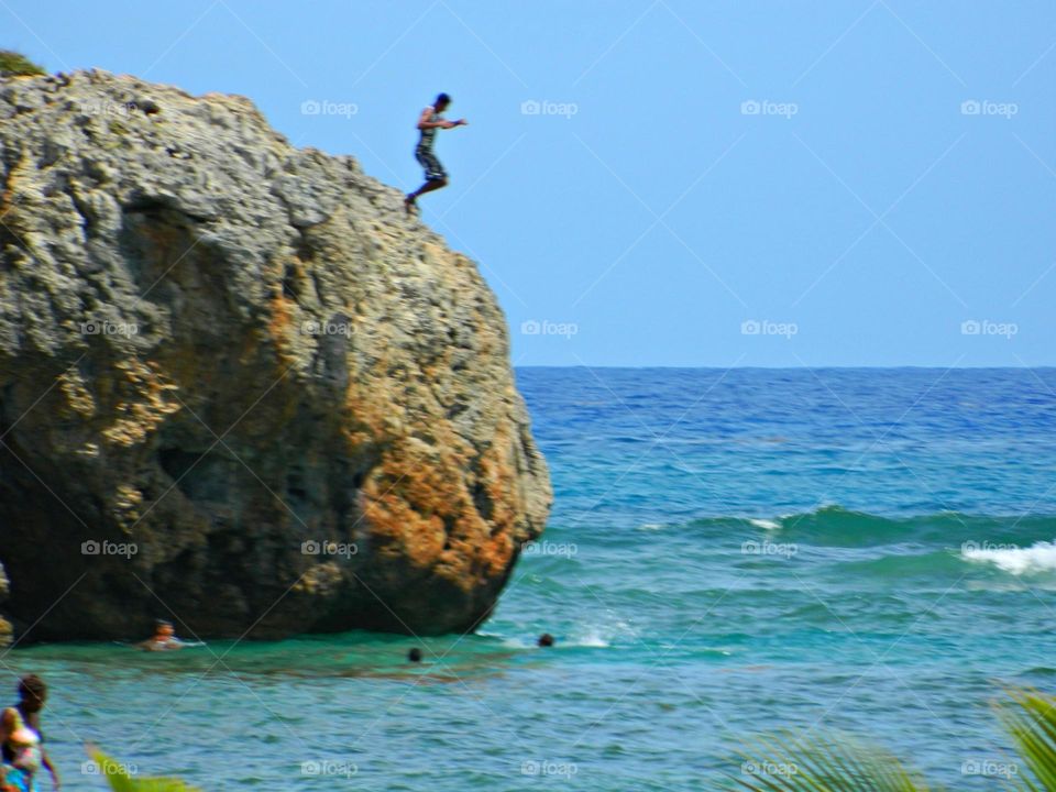 Life in Motion - a young man jumps into the Caribbean Sea from the ledge of a gigantic rock