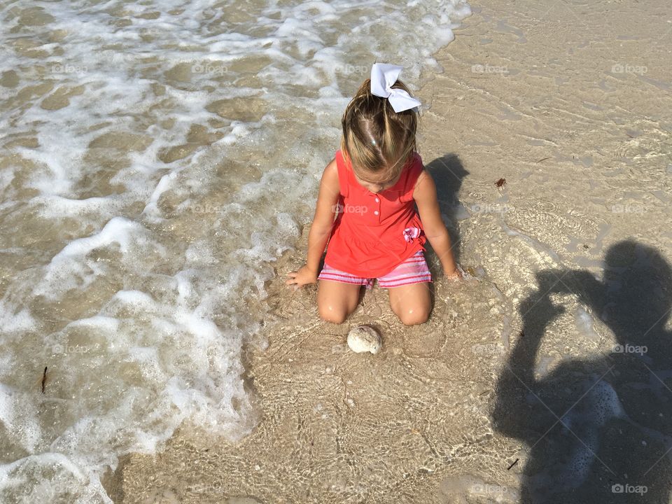 Cute little girl playing with sand on a Yucatan Peninsula beach 
