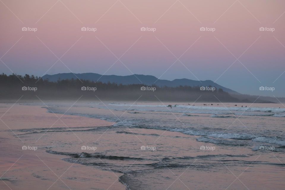 Pink sky reflecting in shallow water after sunset