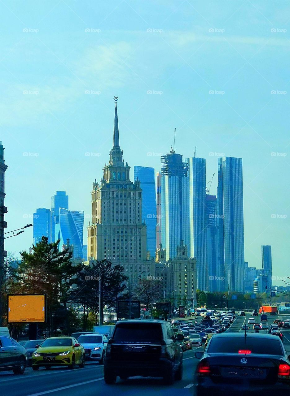 Road through the city.  Skyscrapers in the foreground.A large number of cars. Smoke from cars and from the summer heat