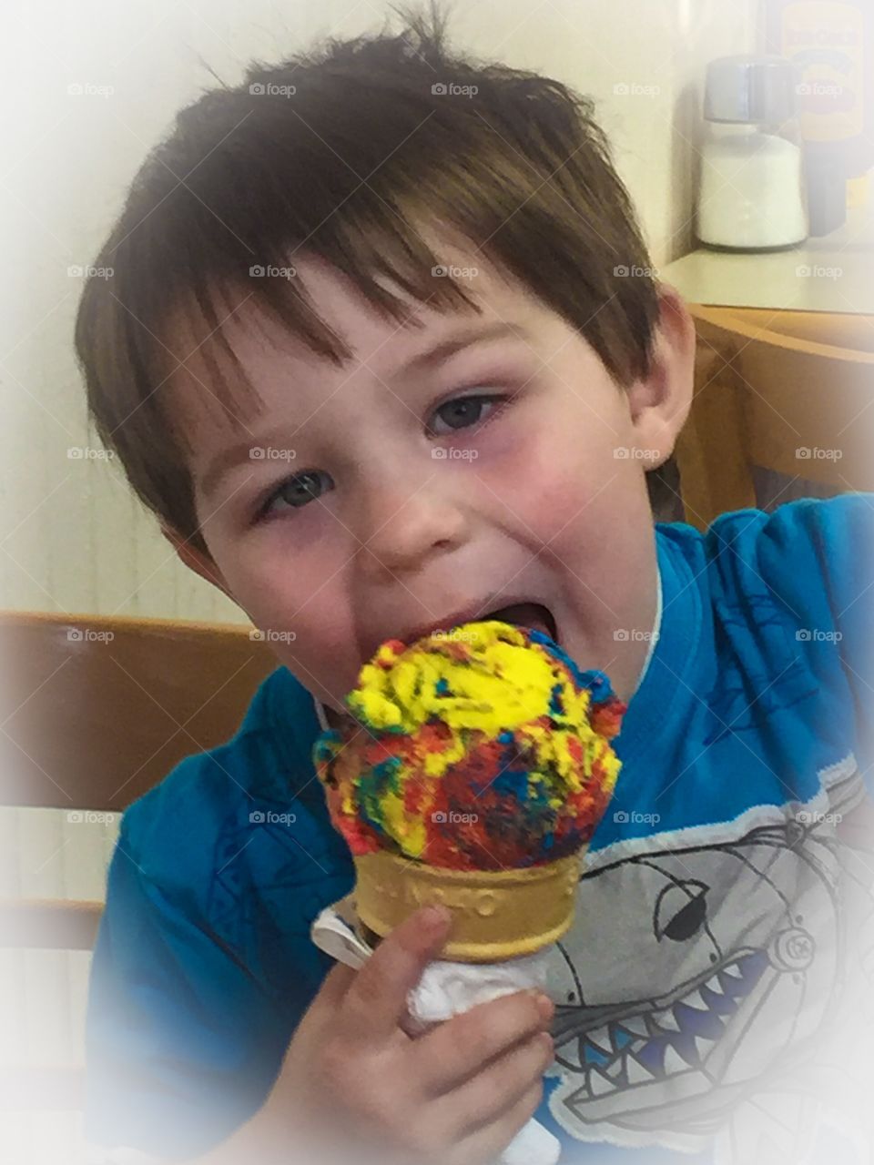 Close-up of a cute boy eating colorful ice cream