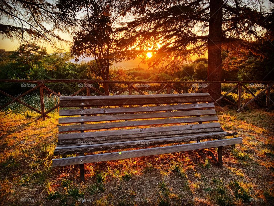 a lonely bench against the backdrop of a fiery sunset