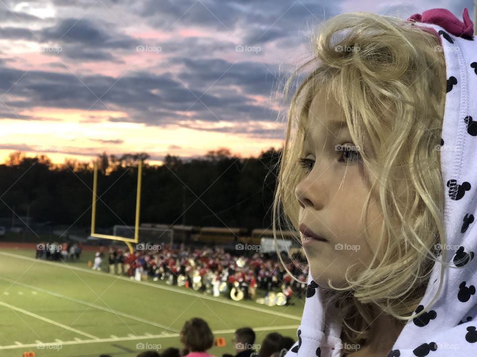 Pretty little girl watching Friday night football 