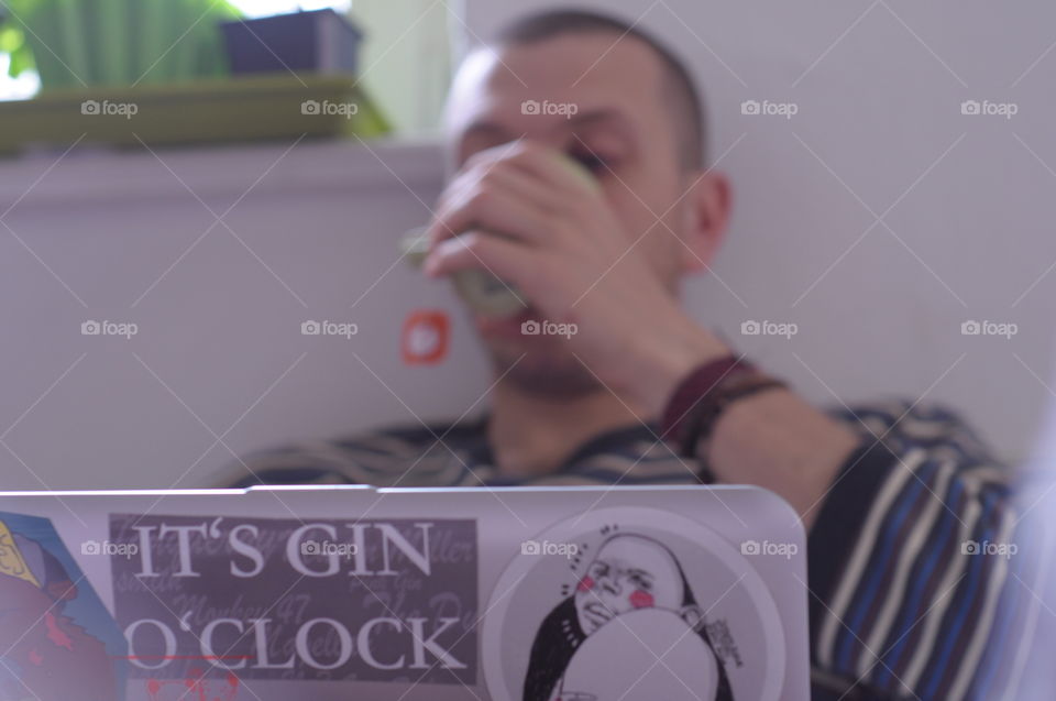 Young man working from home at the computer, drinking tea
