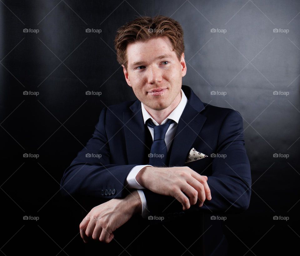 Another man doing portrait photography in a photography studio.
He wears a dress and White shirt.