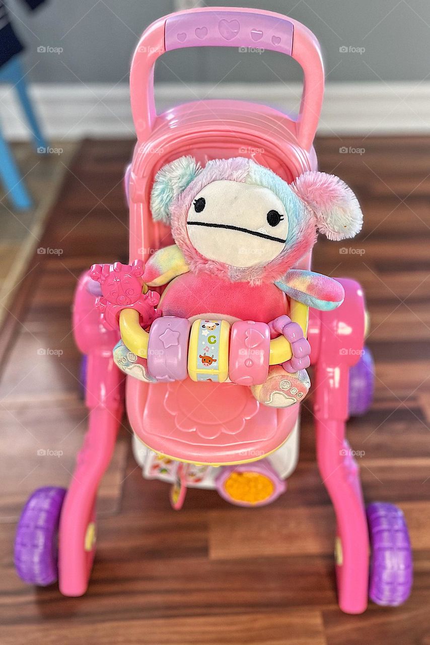 Toddler puts baby into stroller, very pink baby and stroller, toddler plays with toys, children and their toys, playing promotes creativity 