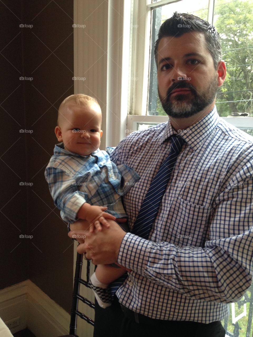 Beard man in formal wear holding son at home