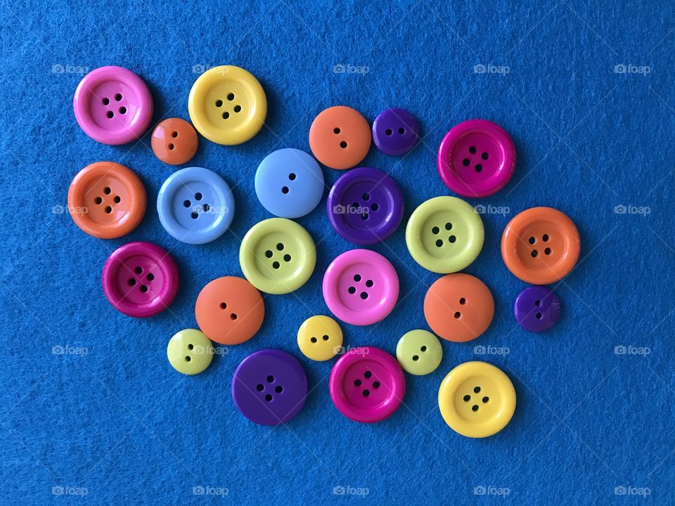 A bunch of colorful buttons on blue felt!