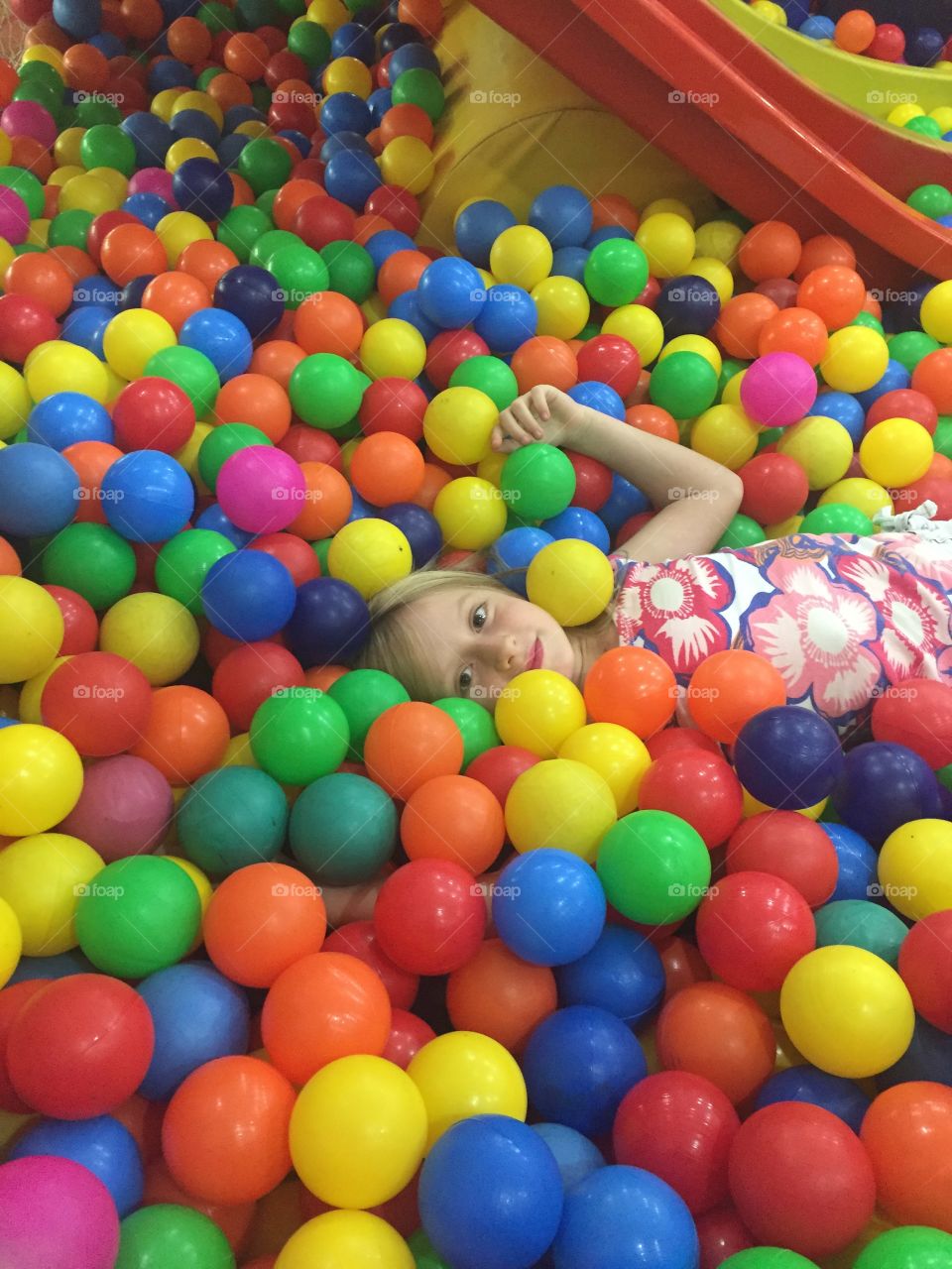 Little girl lying colorful plastic balls