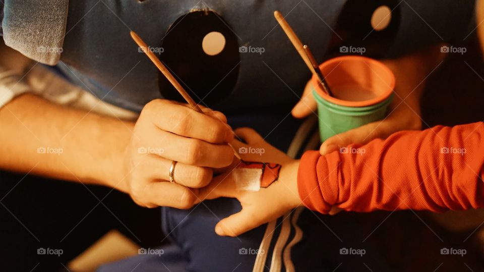 A person painting on child's hand